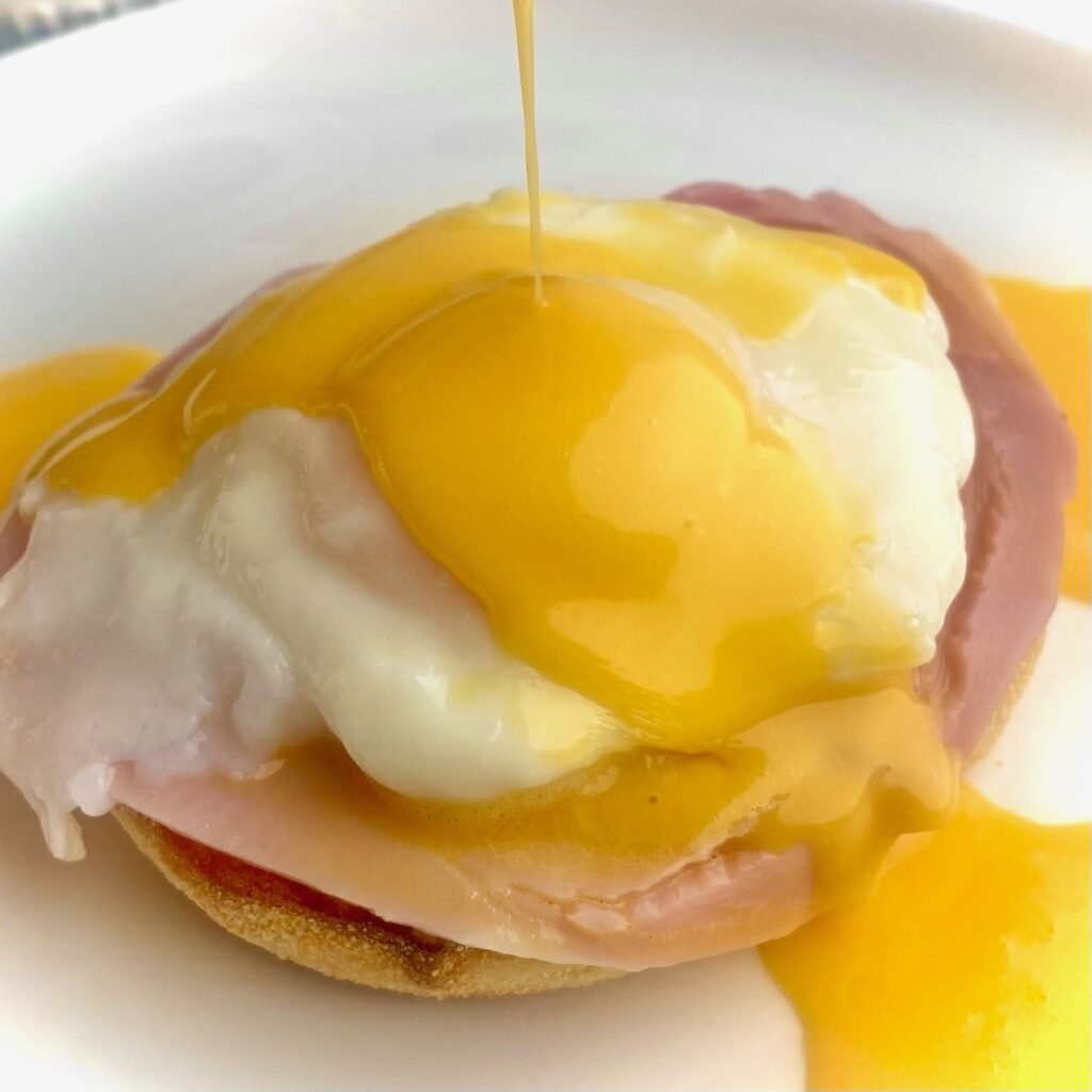 Pouring Hollandaise Sauce over Eggs Benedict