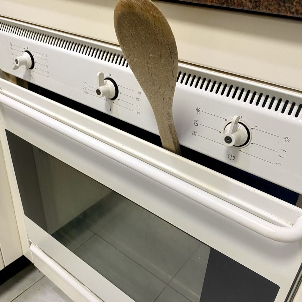 Oven propped open with spoon for Pavlova