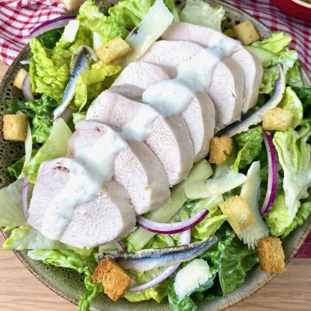 Garnishing Poached Chicken Salad with Garlic Anchovy Dressing
